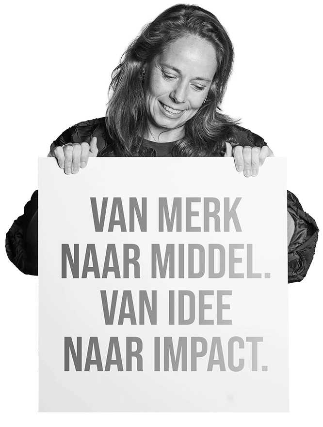 Lydia met bord met tekst: 'Van merk naar middel. Van idee naar impact.'